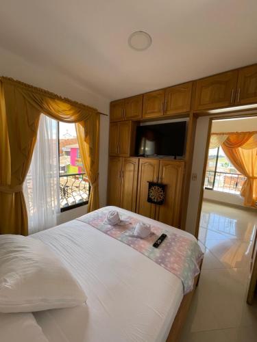 1 dormitorio con 1 cama, TV y ventanas en Apartamento 301 Calle Principal, en Guatapé