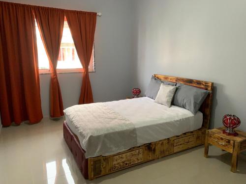 a bedroom with a wooden bed with a window at J Martins Apart Hotel in Tarrafal