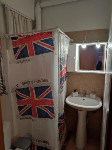 a bathroom with a sink and a shower curtain with british flags at Artemis in Thessaloniki
