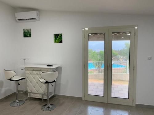 une chambre blanche avec deux tabourets, un comptoir et une piscine dans l'établissement U FILANCIU, à Olmeto