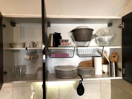 a kitchen cabinet with plates and utensils in it at Studio cinéma in Alès