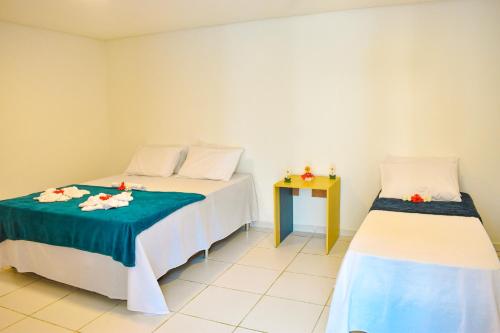 a bedroom with two beds and a side table at Caminho do Paraíso in Porto De Galinhas