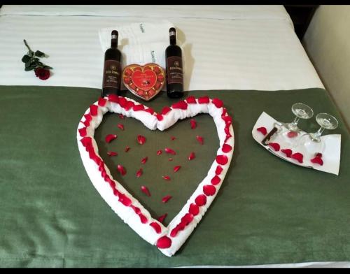 a heart shaped cake on a bed with two bottles of wine at Vila Poienița Căciulata in Călimăneşti