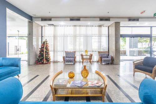 a living room with blue furniture and a christmas tree at Flat Metropoles Ilha do Leite by Easy Home in Recife