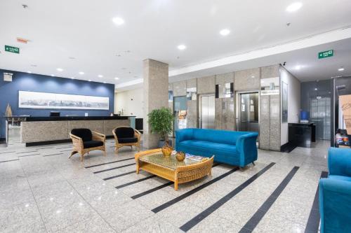 a lobby with a blue couch and chairs and a table at Flat Metropoles Ilha do Leite by Easy Home in Recife