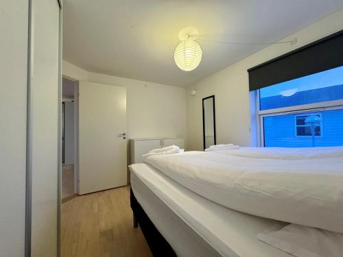 a white bedroom with a large bed and a window at Hotel Nuka in Ilulissat