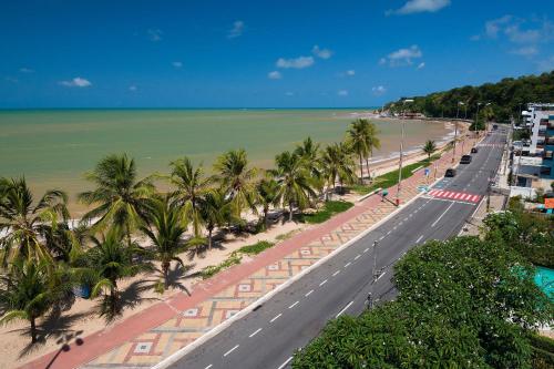 a road next to a beach with palm trees at Flat FM20 Cabo Branco #L5 - By Almare in Tambaú