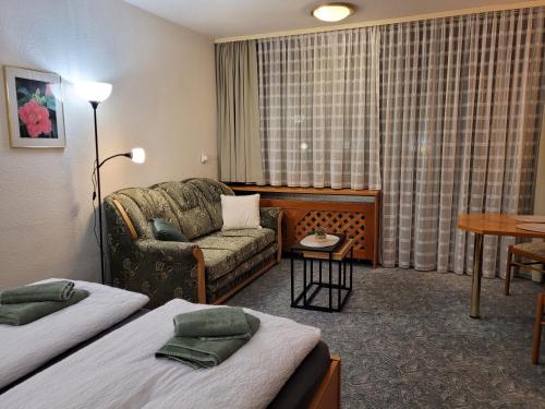 フィリップシュロイトにあるMitterdorf - apartmán Almbergのベッド2台とソファが備わるホテルルームです。