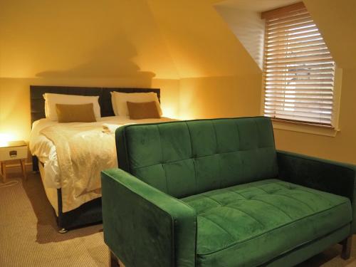 a bedroom with a bed and a green couch at Argyll Hotel in Bellochantuy