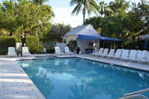 a swimming pool with white chairs and a gazebo at Beautiful Downtown Truman Annex Condo in Key West