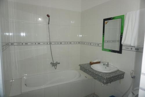 a bathroom with a tub and a sink and a mirror at Minh Nhi Hotel in La Gi
