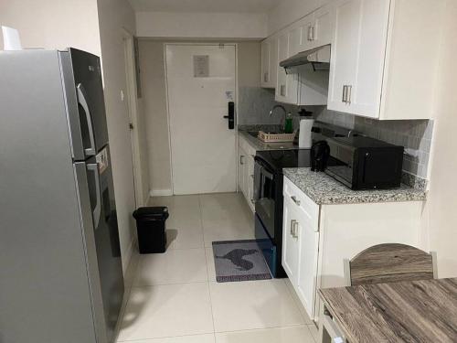 a kitchen with white cabinets and a black refrigerator at Condo with pool in Portmore in Portmore