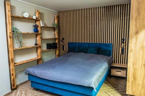 a bedroom with a blue bed and wooden shelves at Pokoje Siódemka in Stegna