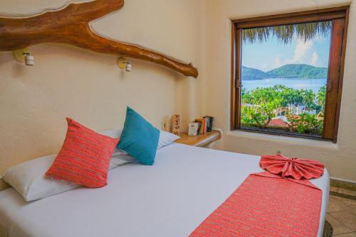 a bedroom with a white bed with a window at Villas San Sebastian in Zihuatanejo