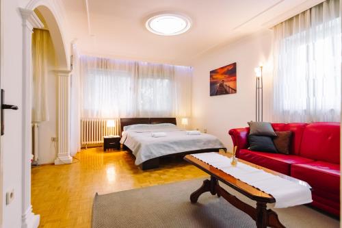 un soggiorno con letto e divano rosso di Apartment Jasna a Belgrado