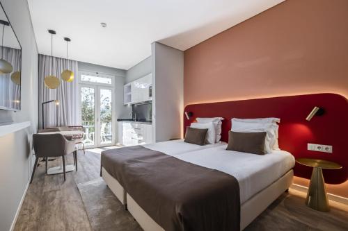 a bedroom with a large bed with a red headboard at King David Suites by Homie in Funchal
