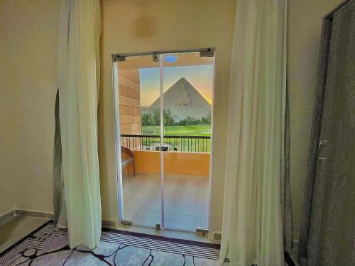 a glass door with a view of the pyramid at Glamour Pyramids Hotel in Cairo