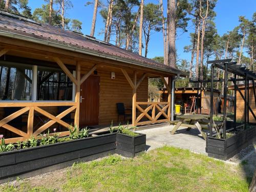 een houten hut met een patio en een picknicktafel bij Domek Dębowy 1 in Lubniewice
