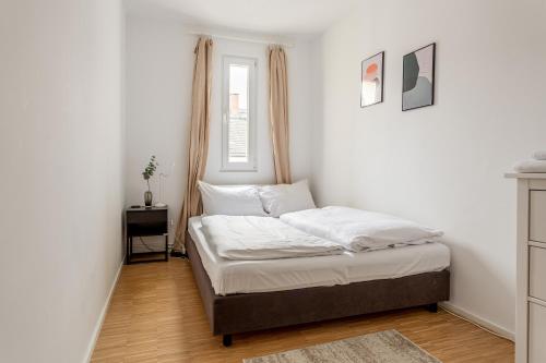 um quarto com uma cama com lençóis brancos e uma janela em Global Living - Design Apartment I Central I Smart-TV I Kitchen I Berlin em Berlim