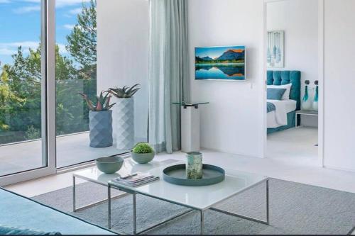 a white living room with a table and a large window at Costa d'en Blanes villa SeA ViEw in Costa d'en Blanes