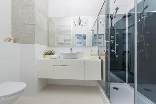 uma casa de banho branca com um lavatório e um chuveiro em Apartment 1-bed Kłobucka P&O Serviced Apartments em Varsóvia