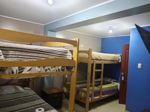 2 literas en una habitación con una pared azul en Hostal Milagros, en Chancay