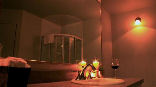 La salle de bains est pourvue d'un lavabo avec des bougies et d'un verre de vin. dans l'établissement Hôtel Val-des-Sources, à Asbestos