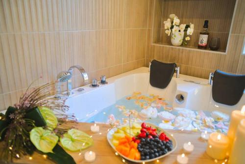 La salle de bains est pourvue d'une baignoire et d'un bol de fruits sur une table. dans l'établissement JapanRoom Jacuzzi&Sauna Haut de gamme parking free, à Mulhouse