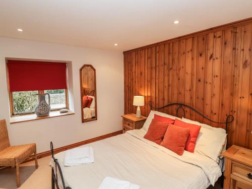 1 dormitorio con 1 cama con pared de madera en 3 Home Farm South en Rousdon