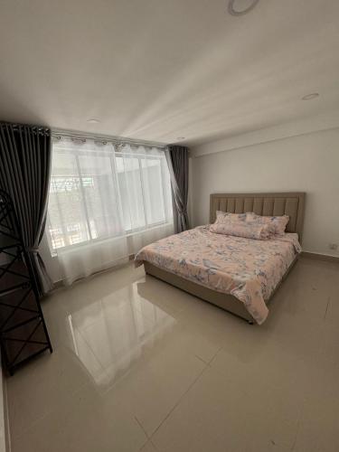 a bedroom with a bed and a large window at Superbe Maison Khmer in Phnom Penh