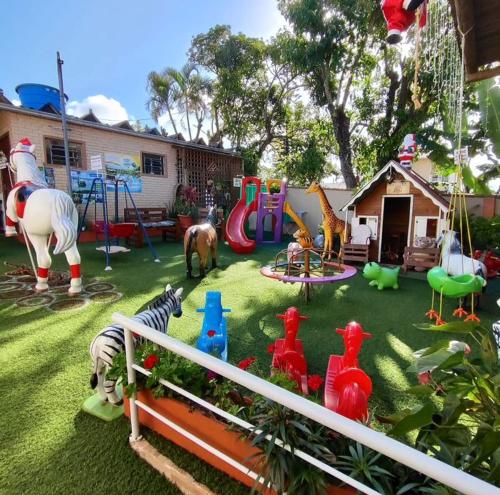 um quintal com um parque infantil com animais de brinquedo na relva em Pousada Alegria do Cowboy em Penha