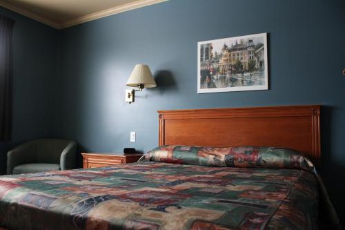 ein Hotelzimmer mit einem Bett und einer Lampe in der Unterkunft Hôtel Val-des-Sources in Asbestos