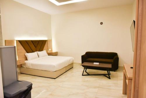 een slaapkamer met een bed, een bank en een stoel bij بيوت عطلات دور المصيف للضيافة السياحي in Qarār