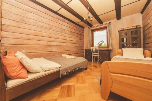 a bedroom with two beds in a wooden wall at Dworek Ogrodniki, całoroczny dom wakacyjny na wyłączność, basen, sauna, las, staw rybny, altana grillowa, ognisko, pianino, kominek, piec chlebowy, duża ogrodzona posesja in Tuczna