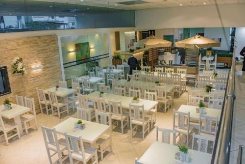 um restaurante vazio com mesas e cadeiras brancas em Hotel San Gabriel em São Paulo