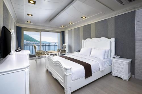 Busan Beach Hotel Busan Songdo في بوسان: غرفة نوم بسرير ابيض وشرفة