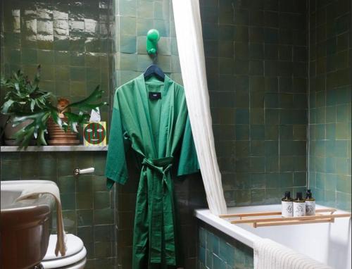 a green robe hanging in a bathroom with a toilet at Suites @ The Townhouse by designer Tobias Vernon in Bath