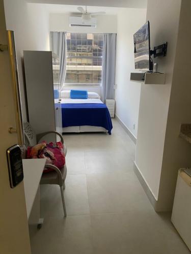 a room with a bed and a chair and a window at Studio Reformado coração Leblon in Rio de Janeiro