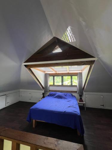 ein Schlafzimmer mit einem blauen Bett im Dachgeschoss in der Unterkunft Fare Tetahora in Tevaitoa