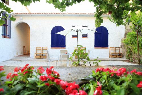 a building with blue doors and a table with an umbrella at Hotel Meli in Castelsardo