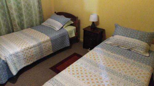 康塞普西翁的住宿－Hostal San Valentín，一间卧室设有两张床和一张桌子上的台灯。