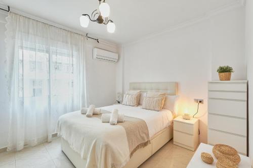 Un dormitorio blanco con una cama y una ventana. en Alice's home delight, en Málaga