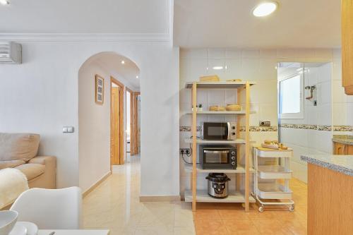 Una sala de estar con cocina y microondas. en Alice's home delight, en Málaga