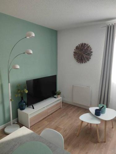 a living room with a flat screen tv and two tables at Studio Calais Front de mer-Le Cocon du Dragon-Classé 3 etoiles in Calais