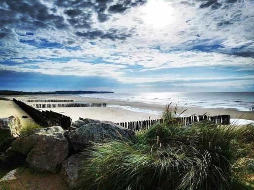 a beach with a fence and rocks and the ocean at Studio Calais Front de mer-Le Cocon du Dragon-Classé 3 etoiles in Calais