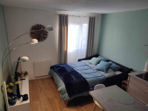 a bedroom with a bed with a blue comforter at Studio Calais Front de mer-Le Cocon du Dragon-Classé 3 etoiles in Calais