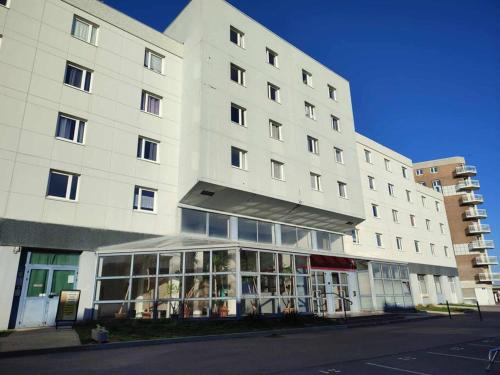 a large white building with a store in front of it at Studio Calais Front de mer-Le Cocon du Dragon-Classé 3 etoiles in Calais