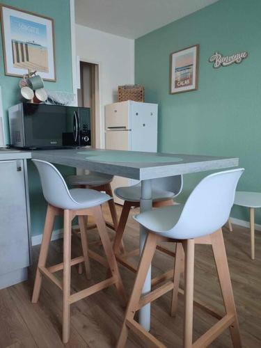 a kitchen with a table and two white chairs at Studio Calais Front de mer-Le Cocon du Dragon-Classé 3 etoiles in Calais