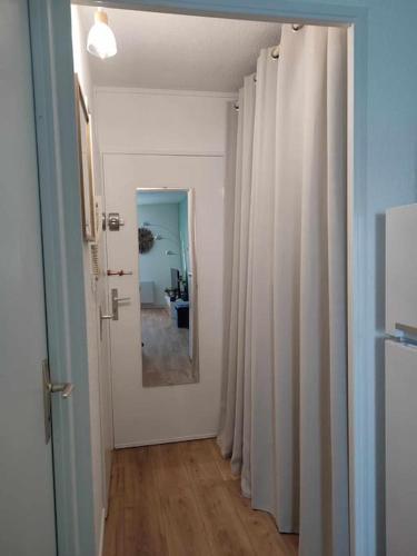 a hallway with white curtains and a mirror at Studio Calais Front de mer-Le Cocon du Dragon-Classé 3 etoiles in Calais