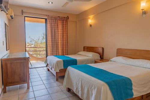 a hotel room with two beds and a window at Hotel El Mirador in Puerto Escondido
